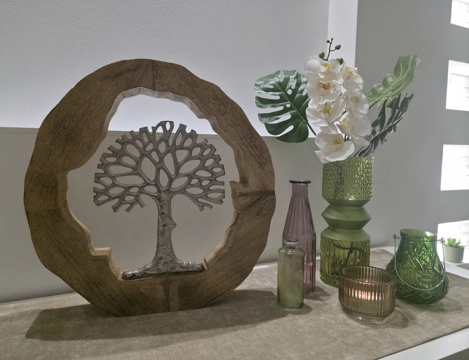 MassageZeit – Massage – Eine Sammlung verschiedener Glasvasen und Kerzenhalter in diversen Grün- und Violetttönen, darunter eine olivgrüne Glasvase von Beliani Vradeto (26 cm).